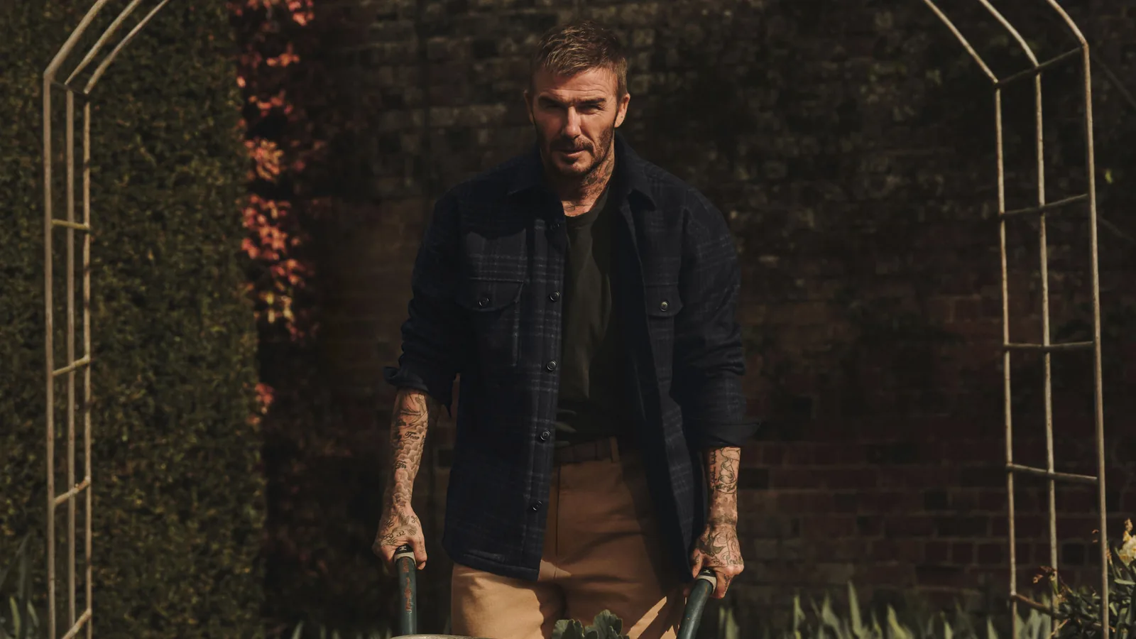 BOSS by Beckham von HUGO BOSS: David Beckham in karierter Hemdjacke mit Schubkarre im Garten
